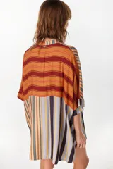 Vestido camisero corto con diseño de paneles combinados en distintos patrones de rayas verticales y horizontales, en tonos rojo, azul, beige y blanco. Posee cuello mao, cierre frontal con botones y mangas cortas caídas.