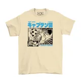Remera de algodón color beige con estampa frontal estilo manga en blanco, negro y azul, que representa una escena de fútbol de la serie Supercampeones con texto en japonés y la frase Dream of a Champion.