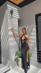 Vestido largo negro con escote halter, abertura en el pecho y tajo lateral.