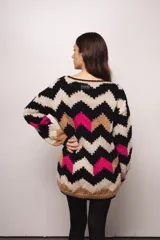 Buzo tejido a mano en lana merino, con diseño de patrón en zigzag multicolor en tonos crema, negro, azul y tostado. Presenta un corte holgado, cuello redondo y mangas largas con puños acanalados.
