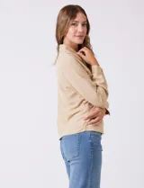 Camisa de crepe color beige con cuello clásico, cierre frontal con botones y dos bolsillos aplicados en el pecho.