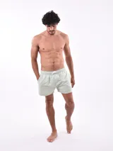 Short de baño blanco con estampado de hojas en tonos azules y rosados, cintura elástica con cordón ajustable.