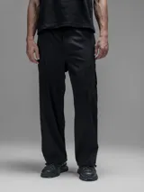 Pantalón cargo negro de corte oversize, confeccionado en microfibra elastizada. Presenta cintura elástica, bolsillos laterales y un bolsillo cargo con cierre de broche a presión. Incluye un sistema de elásticos con tancas en los tobillos para ajustar la apertura.
