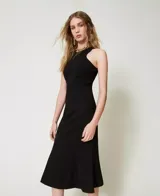 Vestido midi negro sin mangas confeccionado en mezcla de viscosa elástica Milano, con cuello halter, cintura entallada, falda acampanada, costuras verticales, forro y placa con logo Oval T en la espalda.