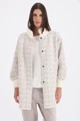 Saco de paño con textura jaspeada en tonos beige y visón, con cuello redondo y cierre frontal con botones a presión. Presenta mangas largas con puños tejidos en color crema y detalles de piel sintética en el cuello.