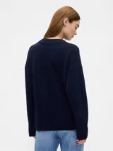 Buzo de punto con cuello en V, manga larga y puños acanalados. Diseño holgado y minimalista.