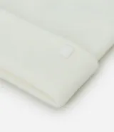 Gorro de punto de estilo beanie, color bordó, con borde plegado y etiqueta decorativa aplicada.