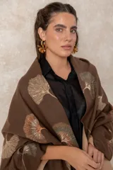 Pashmina reversible de textura suave y caída fluida, con diseño estampado de hojas de ginkgo biloba. Presenta un lado con fondo oscuro y otro con fondo claro, finalizando en ambos extremos con flecos cortos deshilachados.