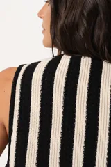 Chaleco tejido a rayas verticales en color negro y crudo, con escote en V y cierre frontal con ganchitos.