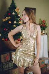 Vestido corto negro con estampado de plumas doradas, escote en V, breteles finos cruzados en la espalda, cut-outs laterales y volado en el ruedo.