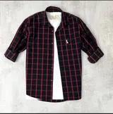 Camisa de manga larga a cuadros negros y rojos, con cuello clásico y cierre con botones.