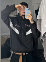 Campera deportiva negra con cuello alto, cierre frontal completo y franjas blancas en las mangas. Presenta estampados en color rosado en el pecho, incluyendo la inscripción "Only F.A.N.S." y gráficos de palmeras con estrellas.