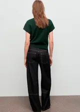 Jersey de punto fino color verde oscuro, con cuello drapeado y manga corta. Presenta un diseño recto y holgado.