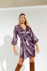 Vestido corto color lila de satén, con escote cruzado, mangas largas abullonadas y lazo en la cintura.