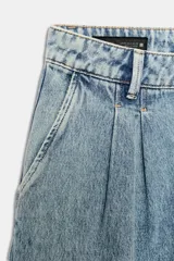 Jeans de tiro medio con pernera ancha, diseño wide leg y pinzas delanteras. Cuenta con bolsillos frontales, bolsillos traseros de plastrón y cierre frontal con cremallera y botón.