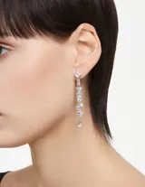 Par de aros largos Swarovski de metal plateado con diseño asimétrico y cristales blancos de diferentes tallas engarzados en cascada.