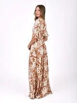 Vestido largo marrón con estampado floral blanco, escote en V cruzado y mangas cortas amplias.