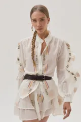 Blusa blanca de viscosa con cuello mao, mangas largas abullonadas y bordados florales en el frente y las mangas.