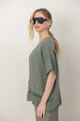 Blusa de lino color blanco, de corte amplio, con escote redondo, mangas cortas y detalle de guarda calada horizontal en la parte inferior.