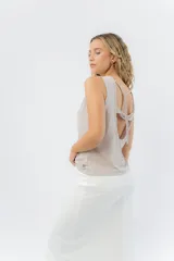 Top sin mangas de lino metalizado con acabado brillante, escote cerrado y espalda abierta con lazo ajustable.