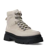 Botas de mujer color beige claro, estilo trekking o montañismo, con caña media y forro interior de borrego o sherpa. Presentan suela track gruesa y dentada de color negro, y sistema de ajuste con cordones y ganchos metálicos.