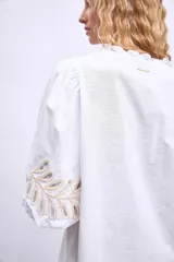 Vestido blanco de lino con escote en V, mangas cortas abullonadas y bordados florales en beige en mangas y ruedo.