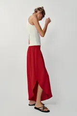 Pantalón fluido de tiro alto en color blanco, con pinzas delanteras, cintura elástica en la espalda y perneras anchas con aberturas laterales pronunciadas.