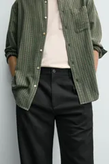Pantalón de corte recto confeccionado en tejido elástico, con cintura elástica, pliegues frontales, bolsillos laterales y bolsillos traseros de vivo con botón.