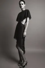 Vestido midi negro de tejido satinado con cuello redondo y manga capa. Presenta detalles de cut-out laterales adornados con encaje a tono. El bajo es asimétrico y tiene cierre en la espalda.