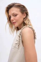 Musculosa color beige con volados en los hombros, confeccionada en mezcla de algodón y Tencel, con cuello redondo y diseño sin mangas.