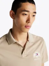 Chomba beige de algodón con cuello clásico, tapeta de dos botones y logo bordado en el pecho.