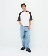 Pantalón de jean azul claro con calce baggy relaxed, cintura con pasantes, cierre tradicional y roturas localizadas en las piernas.