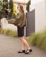 Sandalias de cuero negro charolado estilo romano, con tiras entrelazadas, tira en T y hebilla metálica de ajuste lateral.