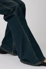 Jeans de denim azul oscuro con lavado vintage, tiro alto y corte acampanado.