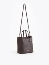 Cartera tipo tote bag pequeña de cuero vacuno negro con diseño de abejas grabadas en bajo relieve. Cuenta con doble asa de mano, correa ajustable y un tag colgante con dije metálico en forma de abeja.