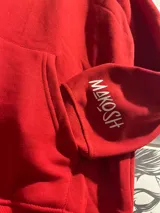 Canguro rojo con capucha y cordones ajustables. Estampado en la espalda con la palabra "NEKOMA" en letras blancas.