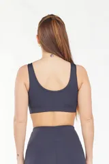 Top deportivo gris oscuro con breteles anchos y espalda deportiva. Incluye copas removibles y está confeccionado en tejido transpirable de secado rápido.