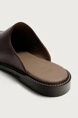 Zueco de piel color marrón oscuro, con diseño liso, horma cuadrada y suela con ligero tacón.