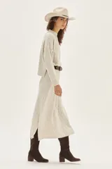 Sweater de tejido bouclé color crudo con cuello alto y sutil brillo por hilos de lurex. Posee mangas largas y un calce relajado.