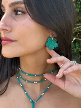 Aros colgantes con dije en forma de flor color verde oscuro, decorados con detalles pintados a mano y argolla de acero.