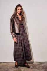 Campera de cuero vegano en tono marrón con acabado desgastado, corte recto y cierre frontal con botones a presión. Presenta cuello clásico y diseño minimalista.