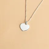 Conjunto compuesto por una cadena de eslabones finos y un dije en forma de corazón liso, ambos fabricados en plata 925.