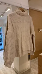 Sweater tejido color crudo con cuello alto y diseño de ochos.