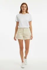 Short de jean color beige de tiro alto, con diseño ajustado al cuerpo, bolsillos funcionales y detalles de roturas en el frente. Presenta un ruedo deshilachado.