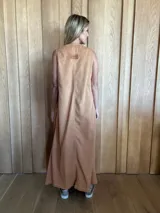 Vestido largo de denim azul, con escote en V, sin mangas, corte holgado, bolsillos laterales y aberturas en los costados de la falda.