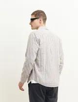 Camisa de lino a rayas verticales color beige y blanco, de corte clásico, con cuello abotonado y mangas largas.