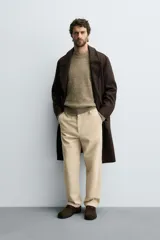 Pantalón de corte regular fit confeccionado en pana de algodón color beige, con bolsillos frontales, bolsillos traseros de plastrón y cierre frontal con cremallera y botón.