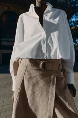 Camisa de popelín color blanco, con cuello solapa, manga larga y bajo abullonado con elástico interior. Cierre frontal con botones.