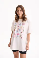 Remera oversize de algodón blanca con estampado multicolor de motivos veraniegos y la frase "Dolce Vita" en el centro.