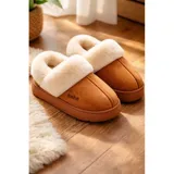 Pantuflas de gamuza color beige con plataforma y forro interior de corderito sintético. Presentan un diseño sin talón con el nombre de la marca bordado en el lateral.